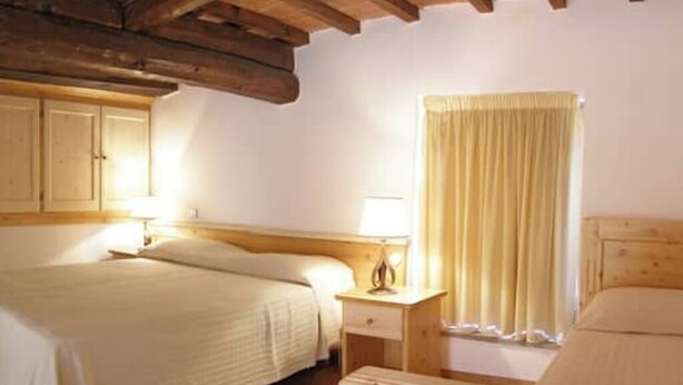 A bedroom with a wooden ceiling, a bed with a headboard, a bedside table with a lamp, and a window with curtains. - Apartment 29 Surrounded by Tranquility (Castel del Piano)