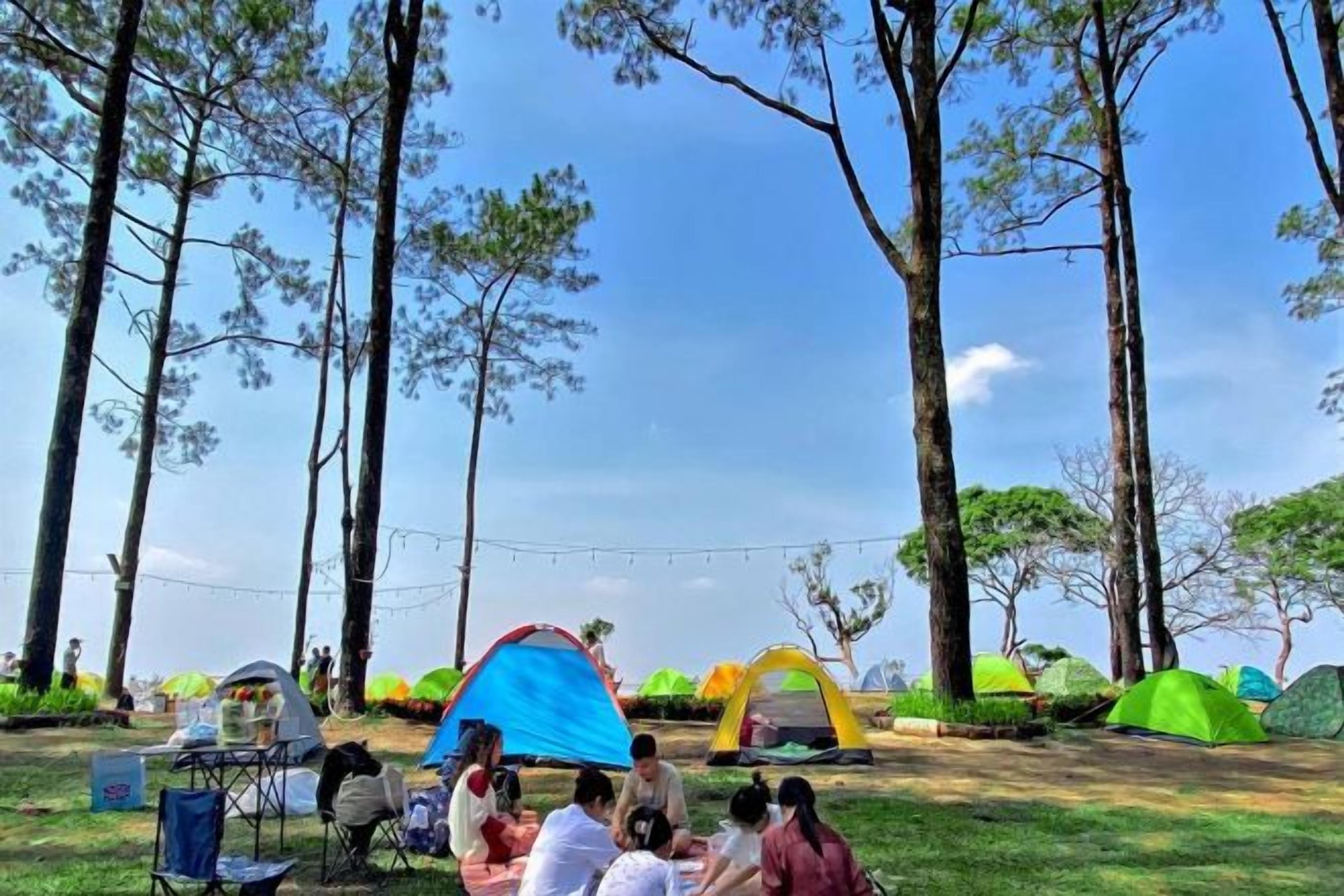 Um camping com tendas e um grupo de pessoas sentadas na grama.