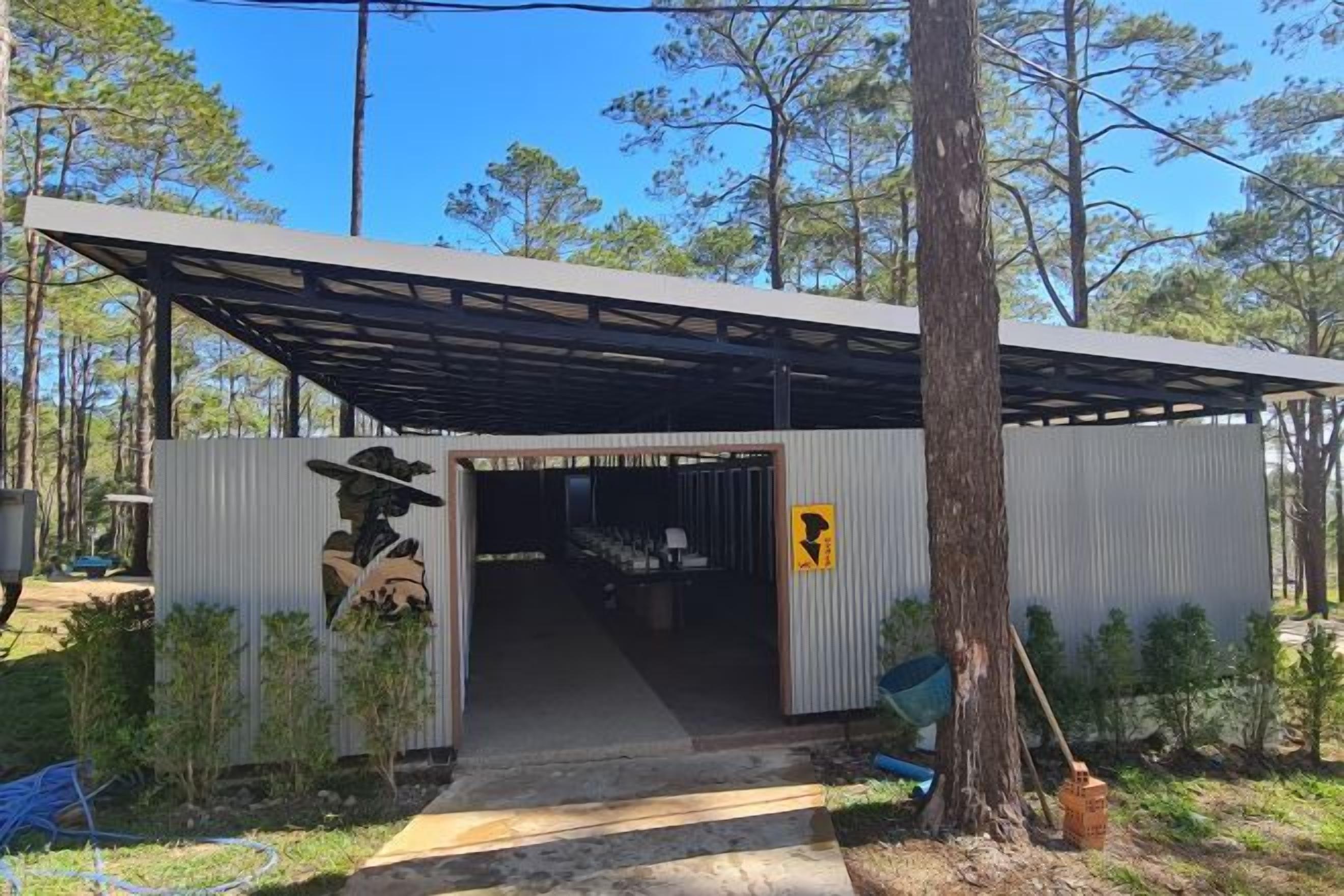 A metal building with a covered entrance and a sign indicating a restroom.