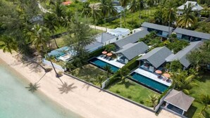 A beachfront property with multiple buildings, a swimming pool, and palm trees. - Baan Talay BeachFront Pool Villa A (Koh Samui)