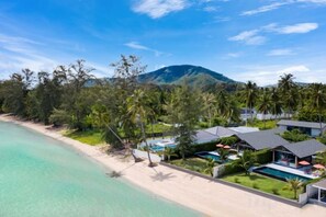 A beachfront property with a swimming pool, a beach, and a mountain in the background. - Baan Talay BeachFront Pool Villa A (Koh Samui)