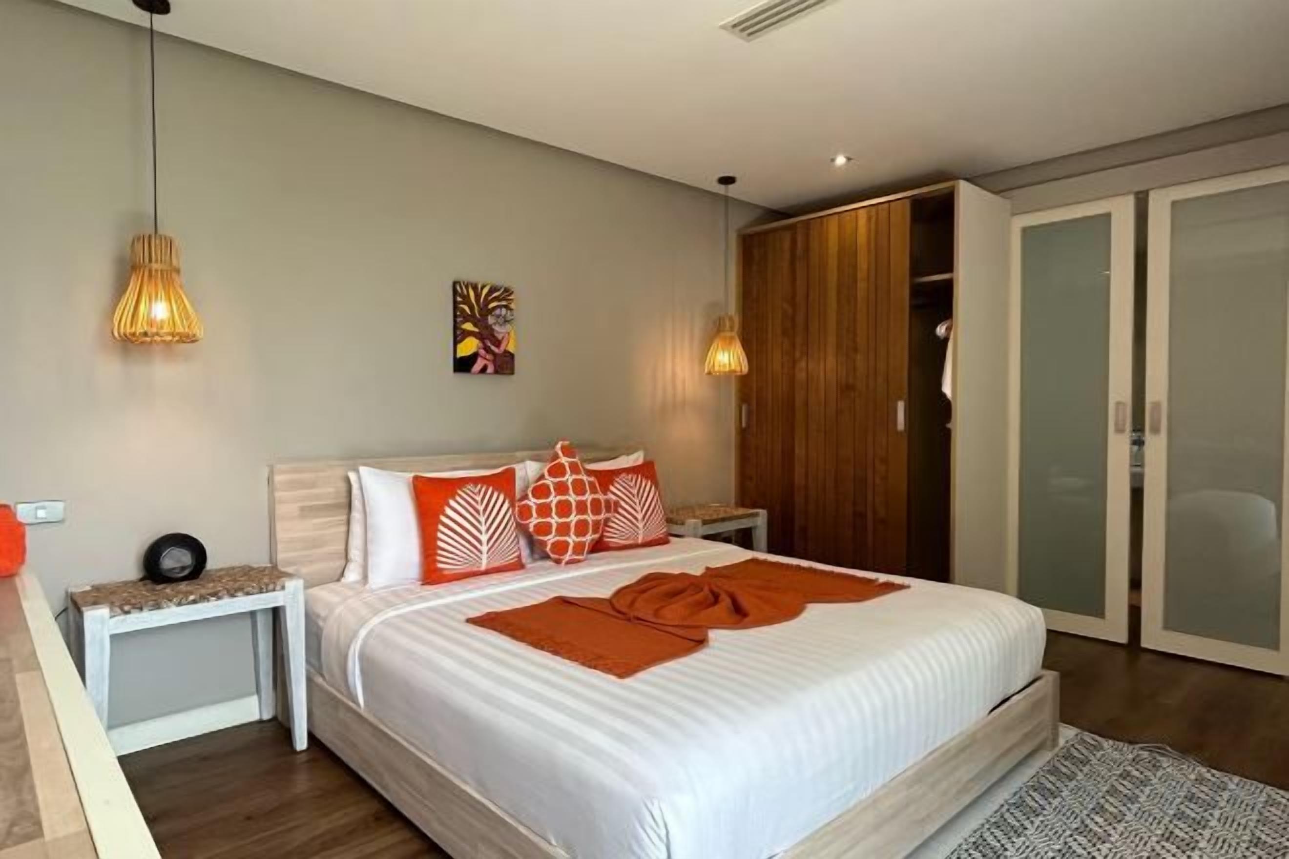 Un dormitorio con cama, mesitas de noche, armario y closet con puerta corrediza.