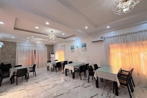A dining area with marble flooring, tables, chairs, and a chandelier. - Star Wish Business Hotel (Ikeja)