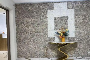 Una habitación con pared texturizada, una pequeña mesa redonda con base dorada y un jarrón con flores.