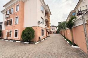 A multi-story residential building with a paved driveway and a small tree in the foreground. - Star Wish Business Hotel (Ikeja)