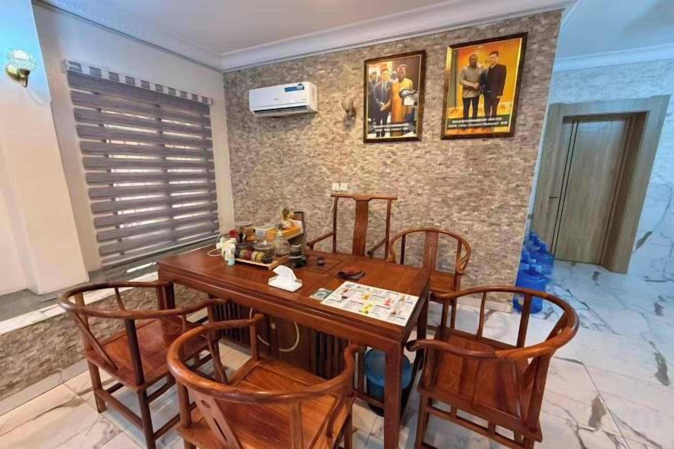 Un comedor con una mesa y sillas de madera, un aire acondicionado instalado en la pared y dos cuadros enmarcados.