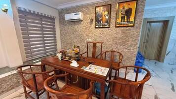 Un comedor con una mesa y sillas de madera, un aire acondicionado instalado en la pared y dos cuadros enmarcados.