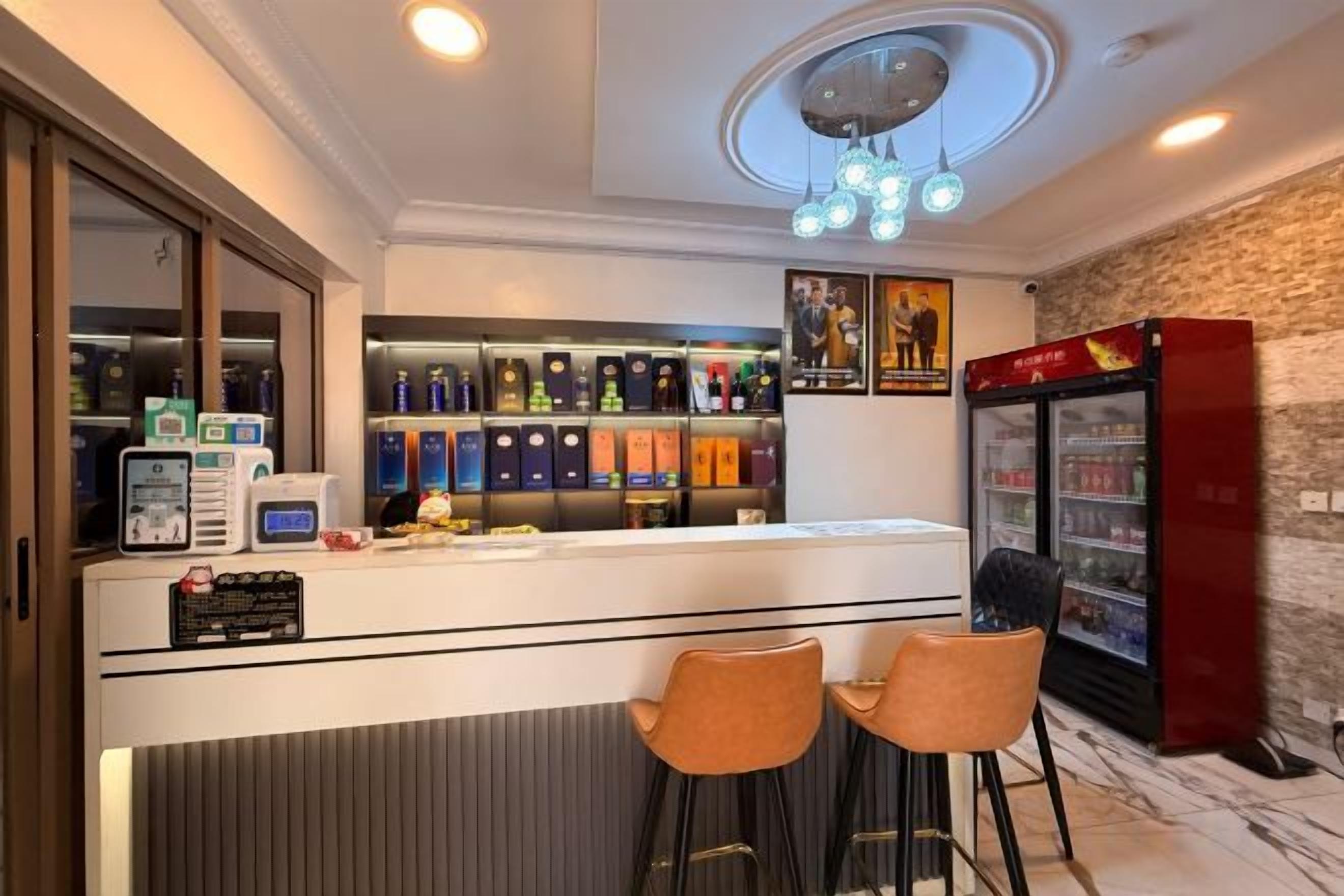 Zona de bar con mostrador, dos taburetes, un refrigerador y una lámpara en el techo.