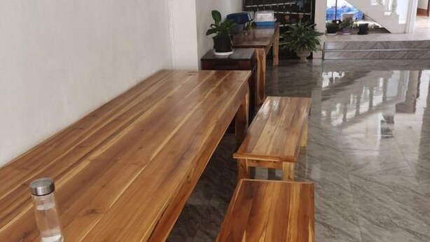 Un banco de madera con un recipiente de vidrio transparente encima, sobre un suelo de mármol.
