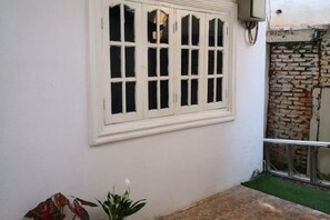 A white wall with a window, a small plant, and a brick wall. - V V Guesthouse (Vang Vieng)