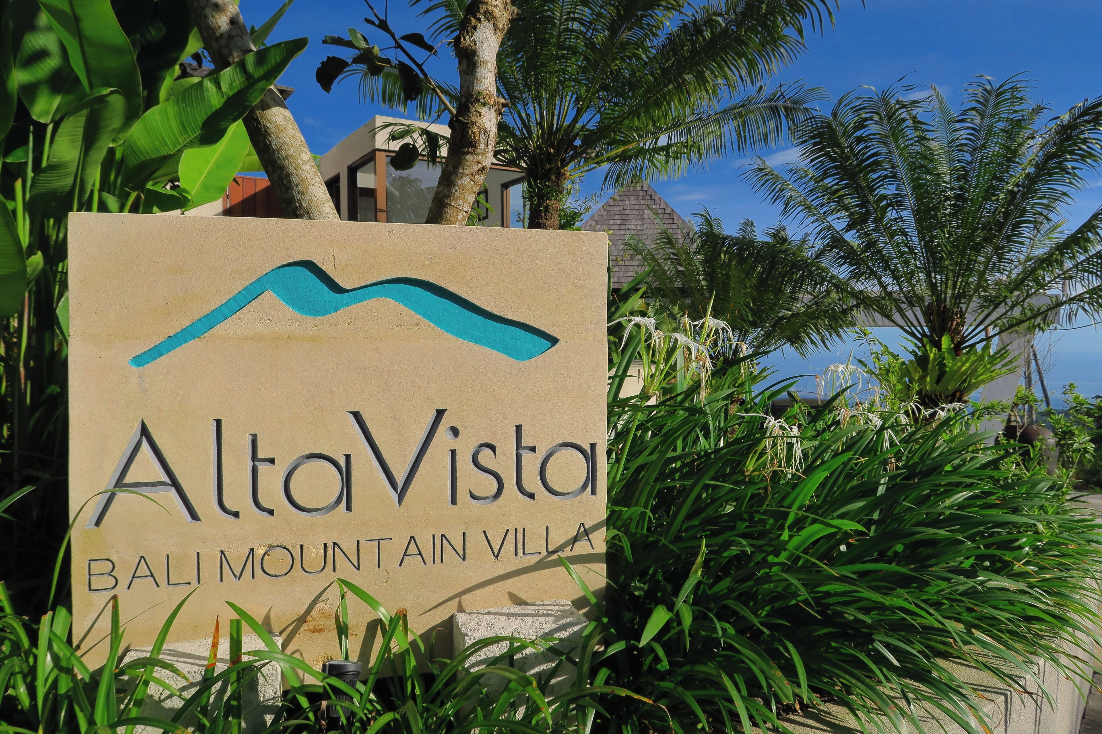 A sign for AltaVista Bali Mountain Villa surrounded by lush greenery.
