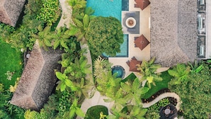 An aerial view of a resort with a central swimming pool, multiple thatched-roof structures, and lush greenery. - ALTA VISTA BALI MOUNTAIN VILLAS (Wanagiri)