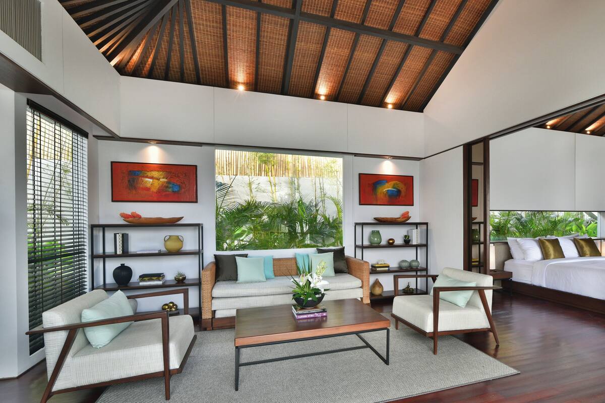 A spacious living area with a large window, a sofa, a coffee table, and a bed.