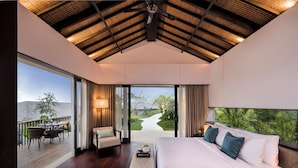 A bedroom with a large bed, a view of a garden, and a balcony with outdoor furniture. - ALTA VISTA BALI MOUNTAIN VILLAS (Wanagiri)