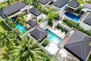 A residential complex with multiple houses, each with a swimming pool and surrounded by greenery.