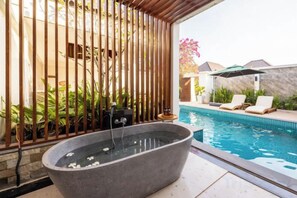 A spa area with a hot tub, a swimming pool, and lounge chairs.