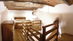 A bedroom with a wooden bed, a nightstand, and a hanging light fixture. - Apartment 22 for 4 Guests (Castel del Piano)
