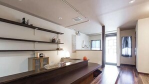 Een modern interieur met een houten receptiebalie, inbouwplanken en een groot raam dat zorgt voor veel daglicht.