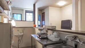 Een kleine keuken met een spoelbak, aanrecht en een klein raam.
