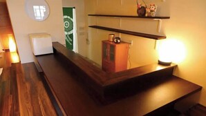 Een houten bank met een inbouwkastje, een klein kastje en een wandplank met decoratieve objecten.
