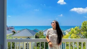 A balcony with a view of the ocean and houses. - Novaworld Phan Thiet - Alala Stay (Phan Thiet)