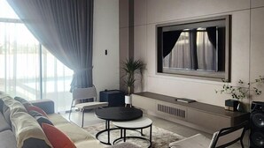 A modern living room with a sofa, a round coffee table, a TV mounted on the wall, and a small side table. - Oceanfront- Laman Green Villa, Port Dickson (Port Dickson)