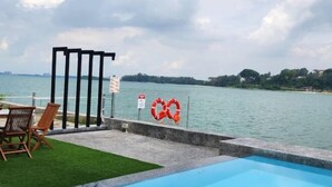 A swimming pool with a view of the water and a distant city skyline. - Oceanfront- Laman Green Villa, Port Dickson (Port Dickson)