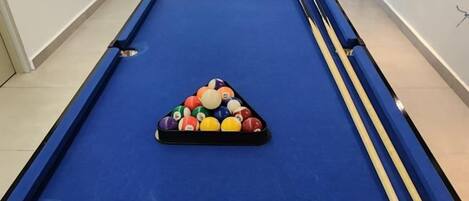 A pool table with a triangular rack of billiard balls and two cue sticks.