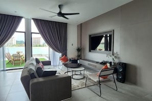 Ein modernes Wohnzimmer mit Sofa, Couchtisch, Fernseher und Deckenventilator.
