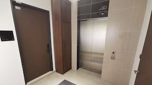 A hallway with a brown door, a lift, and a sign indicating the lift can carry 6 people. - Private Lift 5star Home Seaview Permas / Senibong Cove / Mid Valley Johor (Masai)