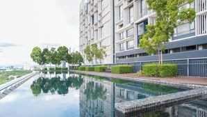 Ein modernes Wohngebäude mit Schwimmbecken, umgeben von Grünflächen und blauem Himmel.