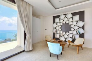 A modern hotel room with a large window, a decorative wall piece, and two chairs. - Turquoise Villa 2 GYM and KIDS ROOM (Koh Samui)