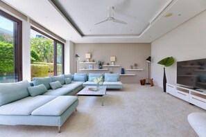 A modern living room with a sectional sofa, a coffee table, a TV, and a ceiling fan. - Turquoise Villa 2 GYM and KIDS ROOM (Koh Samui)