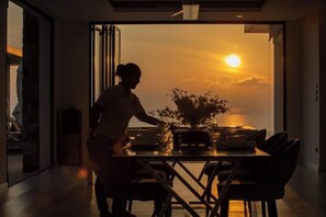 A person arranging a table with a vase of flowers, a laptop, and a smartphone. - Turquoise Villa 2 GYM and KIDS ROOM (Koh Samui)