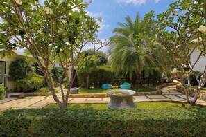 A landscaped garden with a stone planter, palm trees, and a pathway. - Turquoise Villa 2 GYM and KIDS ROOM (Koh Samui)