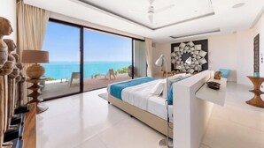 A modern hotel room with a large bed, a desk, and a view of the sea. - Turquoise Villa 2 GYM and KIDS ROOM (Koh Samui)