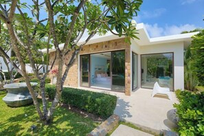 A modern house with a glass door entrance, a well-maintained garden, and a clear sky. - Turquoise Villa 2 GYM and KIDS ROOM (Koh Samui)