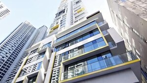 A modern high-rise building with multiple floors, large windows, and a prominent yellow accent. - Spacious Southern Cross Stay, Cozy & Central Home (Melbourne)