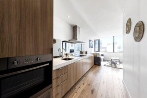 A modern kitchen with wooden cabinets, a built-in oven, and a large window overlooking the city. - Spacious Southern Cross Stay, Cozy & Central Home (Melbourne)
