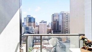 A high-rise building with a cityscape view through a glass balcony. - Spacious Southern Cross Stay, Cozy & Central Home (Melbourne)