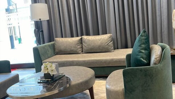 A modern living room with a sofa, a green armchair, a coffee table, and a lamp. - orkide apartment (Phnom Penh)