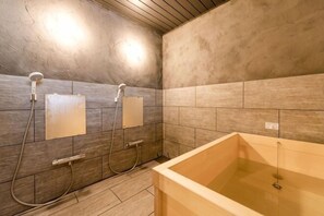 Un baño con una bañera, dos cabezales de ducha y un muro cubierto de azulejos.