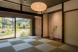 A traditional Japanese room with tatami flooring, sliding doors, and a view of a garden.