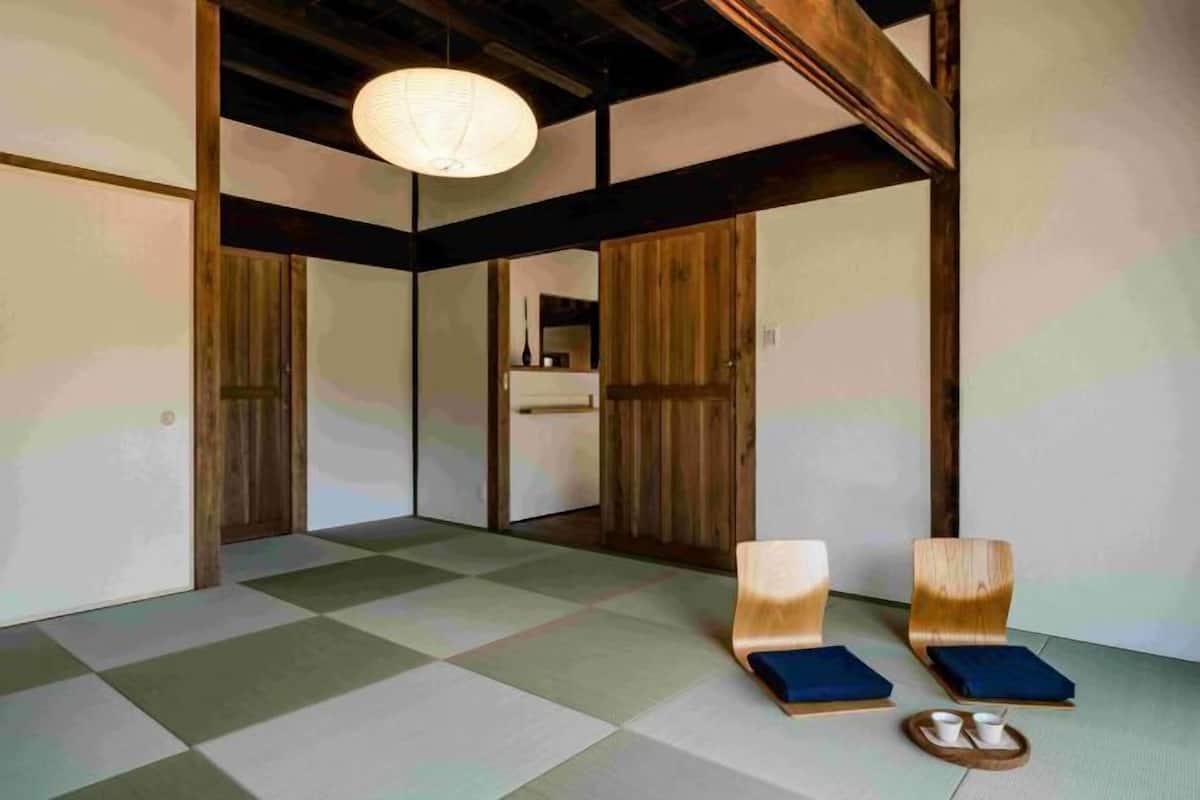 Una habitación tradicional japonesa con suelo de tatami, puertas correderas de madera y techo bajo.