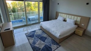 Una camera d'albergo moderna con un letto grande, una scrivania e vista su un balcone.