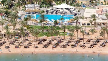Resort com praia, área de piscina e palmeiras.
