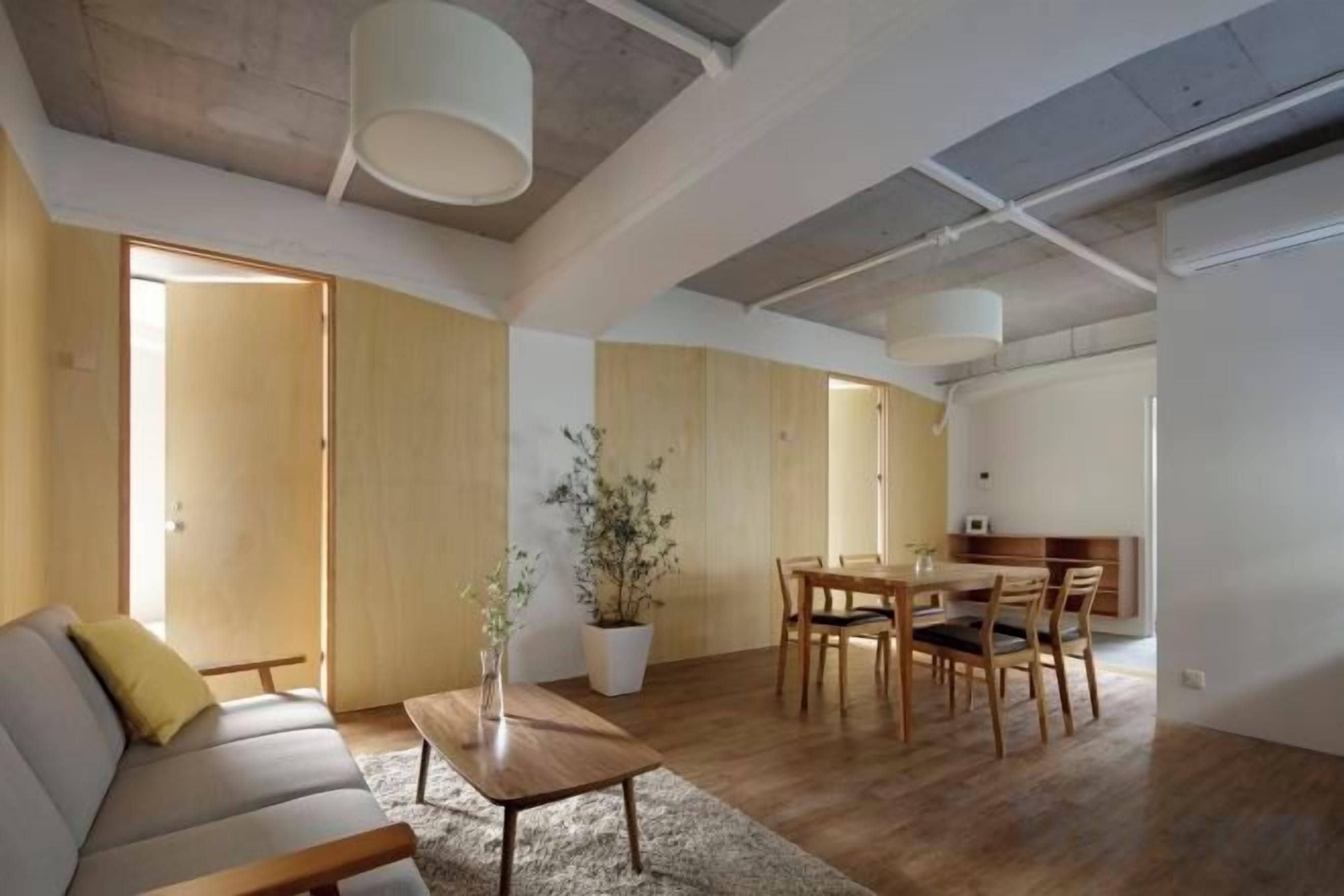 A spacious living area with a sofa, dining table, chairs, and a potted plant.