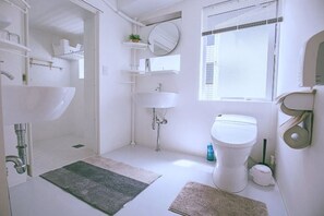 Een moderne badkamer met douche, wastafel, toilet en een raam met zonwering.