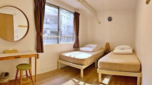 A bedroom with a bed, a desk, a chair, a window with curtains, and a mirror. - TokyoPan B&B (Tokyo)
