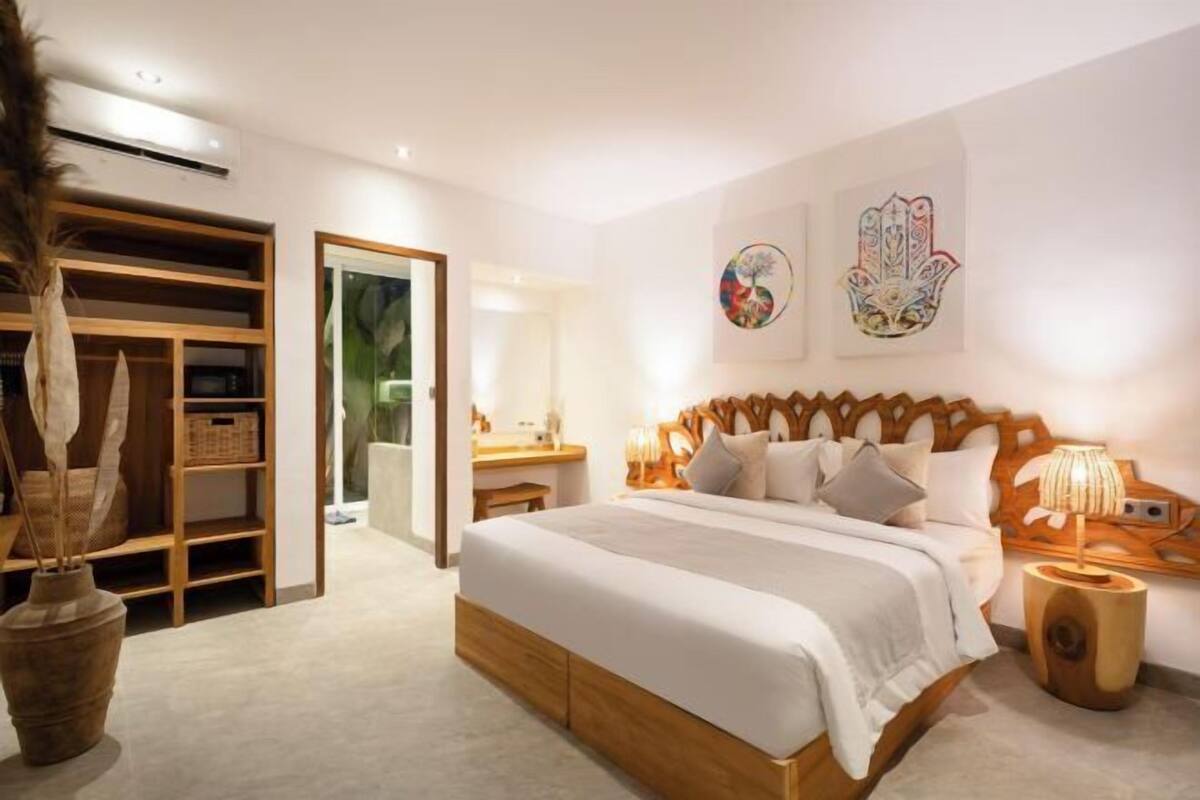 Ein Schlafzimmer mit einem hölzernen Bett, einem Nachttisch, einem Kleiderschrank und einem großen Spiegel.
